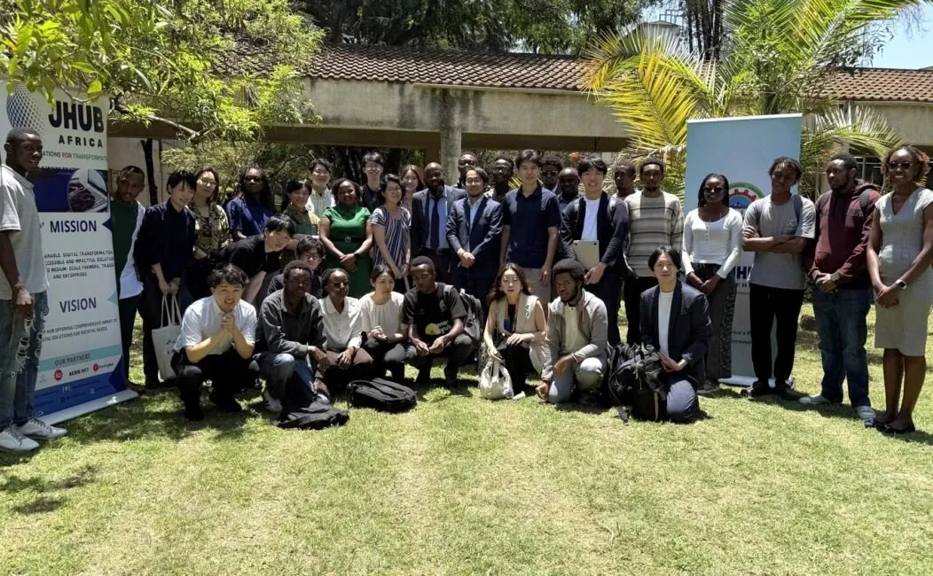 A large group of students and young founders on a lawn at JHUB Africa, between the hub’s banners.